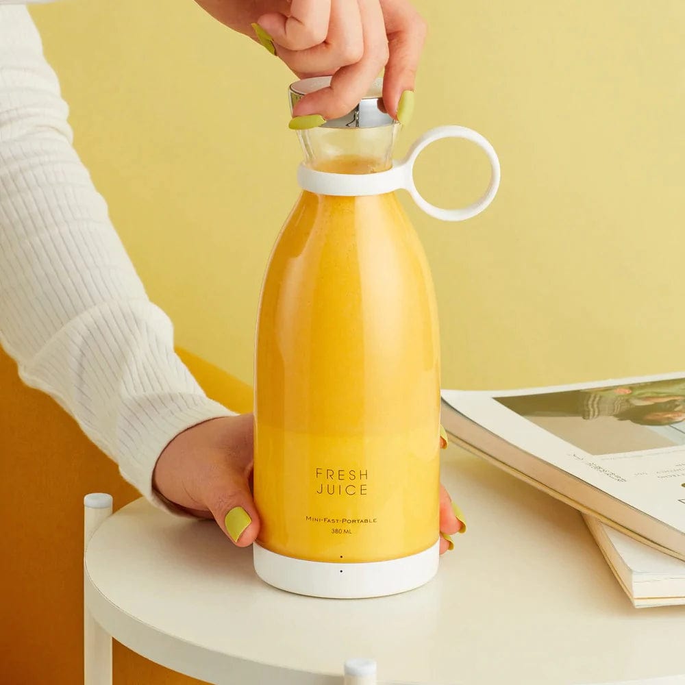 Hand benutzt einen kabellosen Mixer mit Orangensaft.