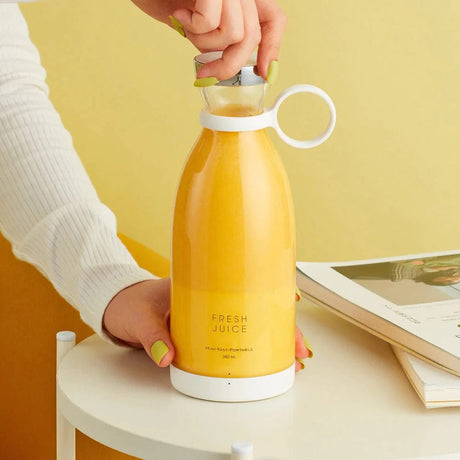 Hand benutzt einen kabellosen Mixer mit Orangensaft