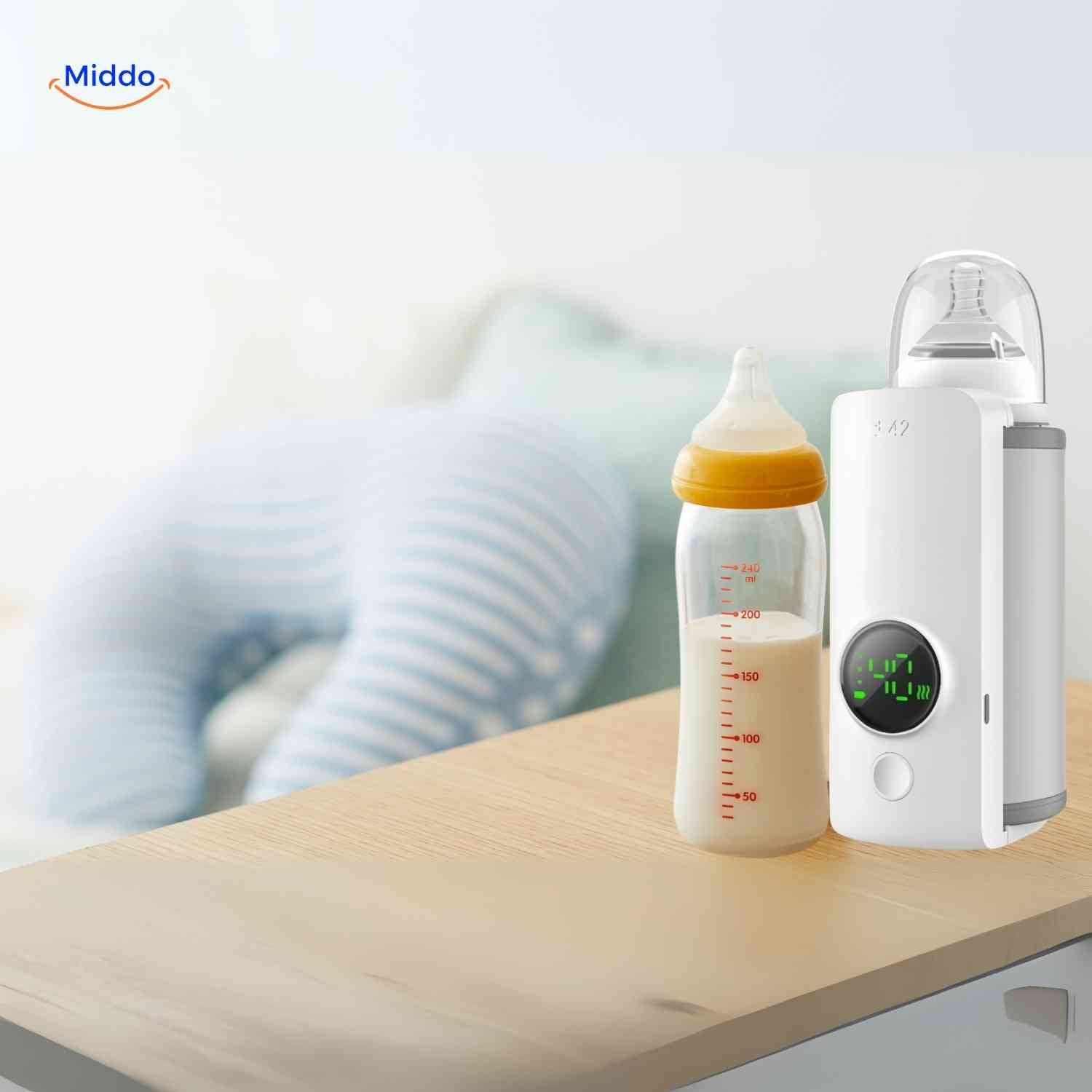 <url>www.middo.nl</url>  
Warmiboo Flaschenwärmer neben der Babyflasche auf dem Tisch