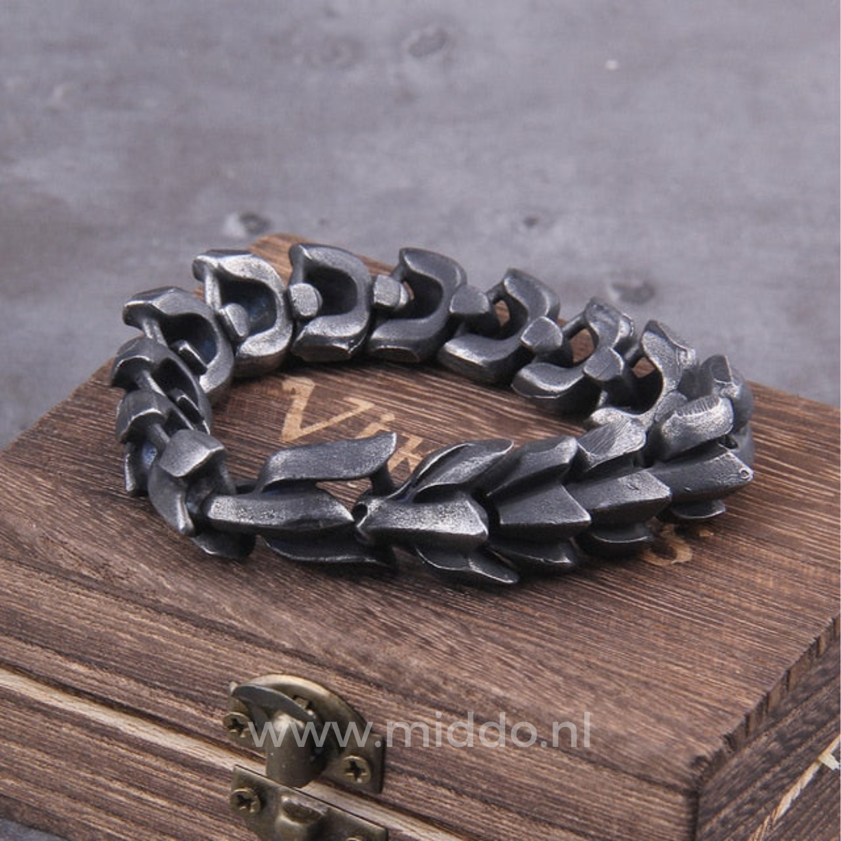 Schwere dunkel-silberne Drachenarmband auf Holzkiste.